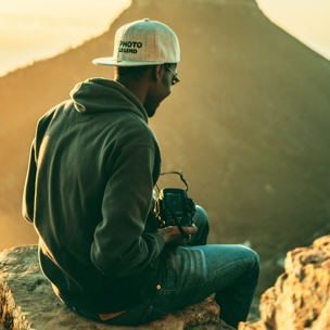 A man holding a camera with beautiful mountain background.